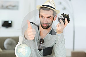 man wearing hat with globe and piggy bank photo