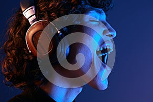 Man wearing headphones listening to music and singing with his mouth open, hipster lifestyle blogger, portrait purple