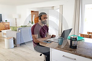 Man wearing headphones using laptop at home