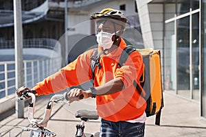 Man wearing helmet with a backpack crossing the road with a bicycle