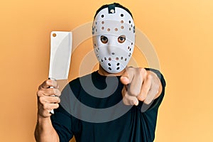 Man wearing hockey mask holding butcher knife looking dangerous and threatening