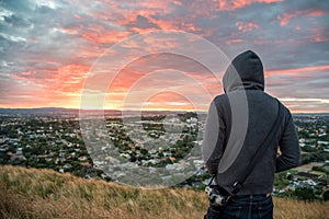 Man wearing hoody watching sunrise over Auckland city