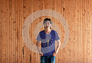 Man wearing India  flag color shirt and standing with two hands in pant pockets on the wooden wall background