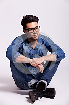 Man wearing jeans shirt and glasses, sitting