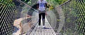 Man wearing jeans standing around a foot over bridge