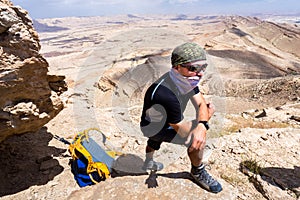 Man wearing keffiyeh standing desert mountain.