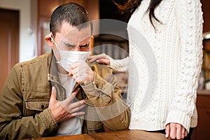 Man wearing a mask and coughing painfully