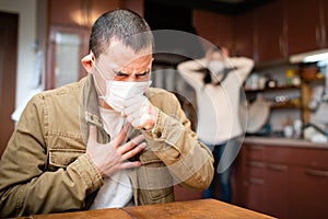 Man wearing a mask and coughing painfully