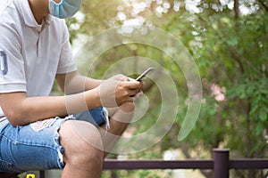 Man wearing a mask and holding a smartphone in the garden