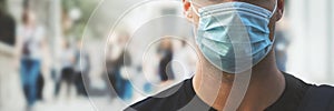 man wearing medical face mask at crowded city street during virus pandemic. copy space