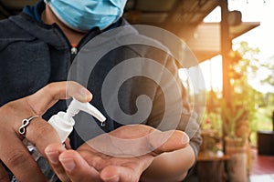 Man wearing medical face mask using hand sanitizer in coffee shop. Man sitting in coffee shop disinfect his hands to avoid covid-