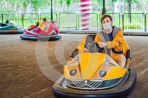 Man wearing a medical mask during COVID-19 coronavirus having a ride in the bumper car at the amusement park photo