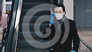 Man wearing a medical mask and gloves to protect against the coronavirus epidemic calls and communicates on a mobile