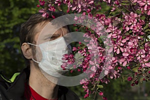 Man wearing a medical mask near blossom tree. Health care concept. Man blurred