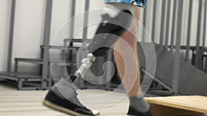 A man wearing a modern robotic exoskeleton on his feet is working out in the gym. Physiotherapy rehabilitation, which