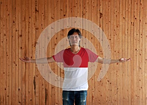 Man wearing Monaco flag color shirt and standing with arms wide open on the wooden wall background