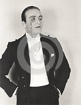 Man wearing monocle and tuxedo with hands in pockets photo