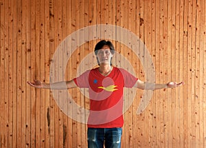 Man wearing New Mon State Party flag color shirt and standing with arms wide open on the wooden wall background