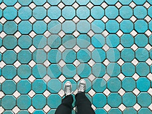 Man wearing old blue sneakers in blue trousers standing on hexagon floor fashion design concept, modern. pattern background