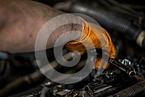 A man wearing an orange glove fixing and doing maintenace on a car engine in an auto repair shop photo