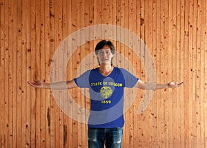 Man wearing Oregon flag color shirt and standing with arms wide open on the wooden wall background