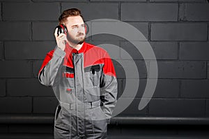 Man wearing overalls with professional earplug on brick wall