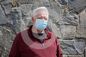 Man wearing a paper mask on his face. A man wears a Medical Face Mask to help avoid contracting Coronavirus aka Covid-19. Covid-19