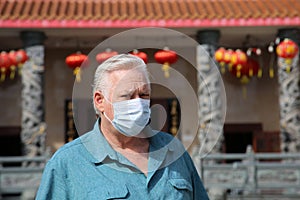 Man wearing a paper mask on his face. A man wears a Medical Face Mask to help avoid contracting Coronavirus aka Covid-19. Covid-19