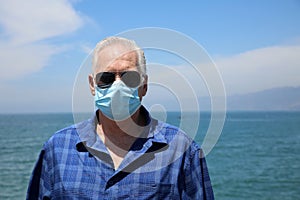 Man wearing a paper mask on his face. A man wears a Medical Face Mask to help avoid contracting Coronavirus aka Covid-19. Covid-