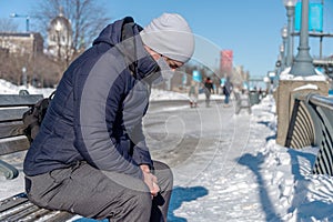 Man wearing a protection mask and sitting on bench during Covid-19 Pandemic