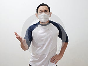 Man wearing protective face mask looking to camera shows annoyed gesture