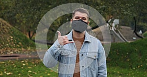 Man wearing protective face mask showing shaka hand sign