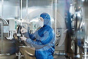 Man wearing protective gear and mask operating equipment at chemical factory