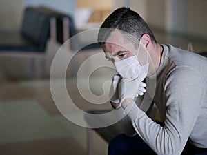 Man wearing protective gloves on hands and mask on face nervously impatiently waiting in the lobby