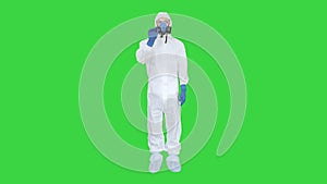 Man wearing protective mask and hazmat suit crossing hands and showing stop gesture on a Green Screen, Chroma Key.