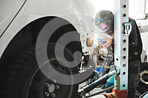 Man wearing protective mask while repairing rear car body with welding machine. Weld of vehicle.