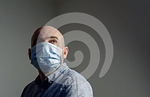 Man wearing protective standard FFP1 antiviral protective face mask looking up