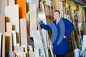 Man wearing protective workwear standing with plywood in store