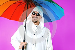 Man wearing raincoat and sunglasses holding umbrella