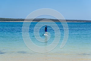 Man wearing rash guard on a stand-up paddle board at the ocean bay in Australia. SUP water sport activity