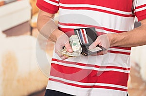 Man wearing red white striped shirt holding wallet