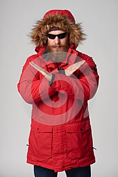 Man wearing red winter jacket gesturing stop enough hand sign