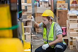 Man wearing safety uniform and yellow hard hat working checking quality wooden products at workshop manufacturing wooden. Male
