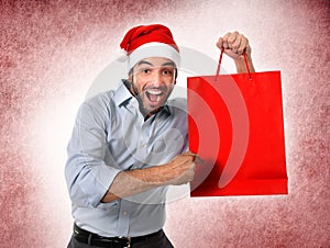 Man wearing santa hat holding Christmas shopping bag smiling happy