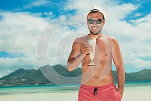 Man wearing shades and drinking a cocktail on the beach