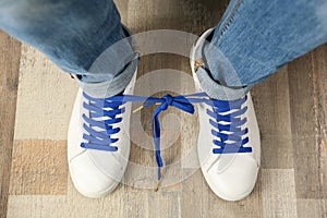 Man wearing sneakers with tied laces, top view. April fool`s day