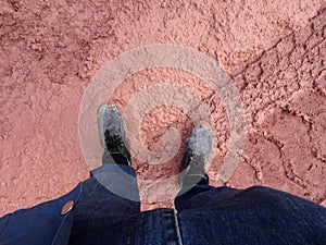 A man wearing steel toe shoes and standing in a mud.