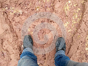 A man wearing steel toe shoes and standing in mud.