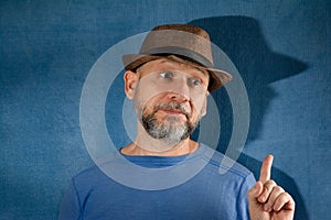 Man wearing a stylish black fedora hat while pointing towards something with a determined expression
