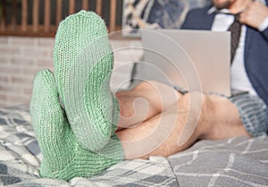 Man wearing suit and underpants in the green socks working at home online sitting on the bed. Focus on the socks